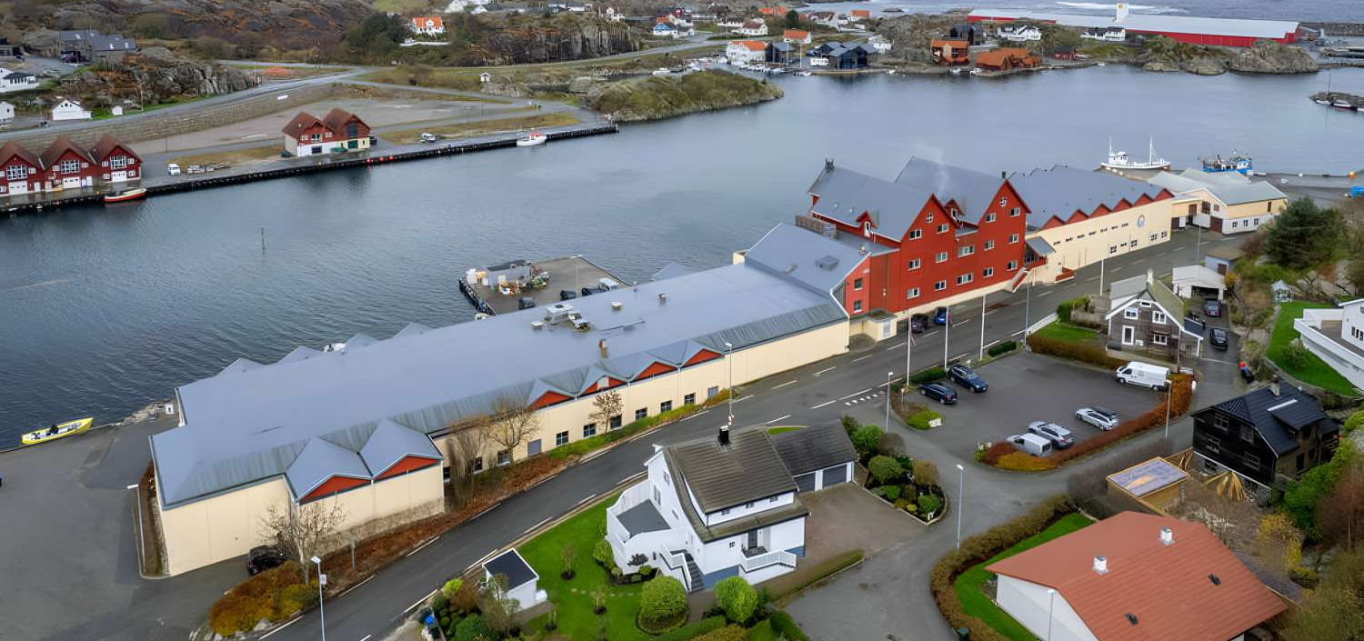 Vågen 42 sett fra luften – det røde og hvite næringsbygget ved kaien i Sirevåg havn